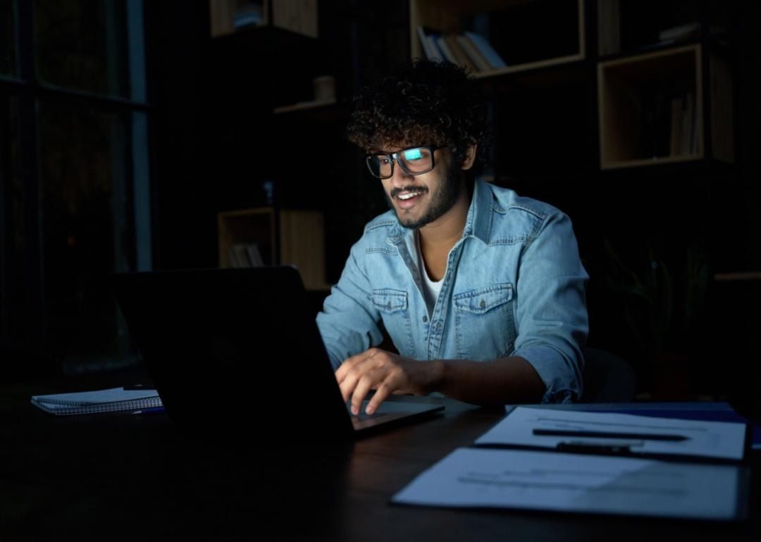 A person working on his laptop in the dark.