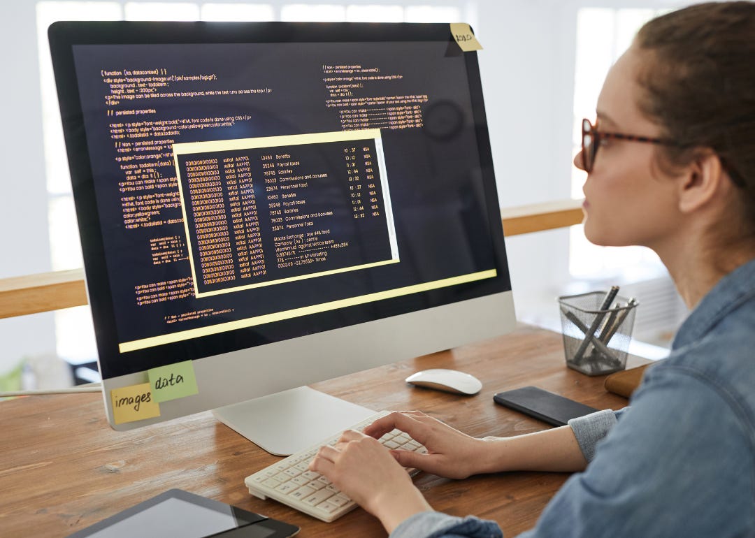 A person writing code on a desktop computer.