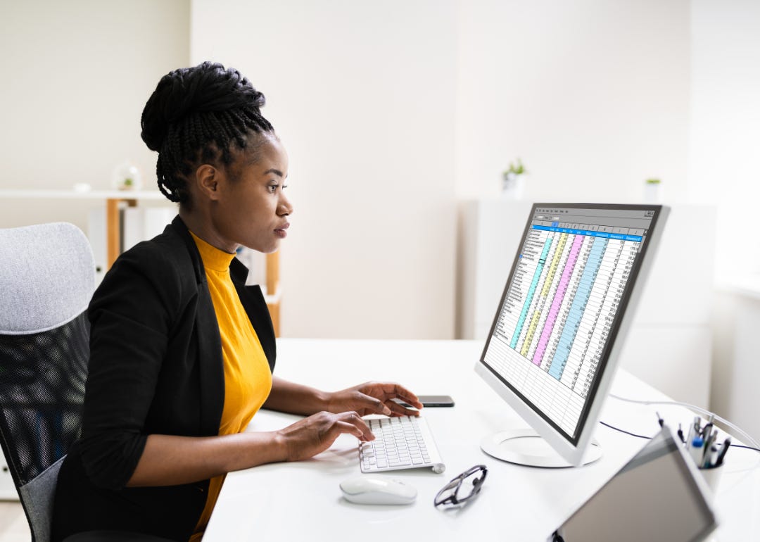 A person working on a spreadsheet on a desktop computer.